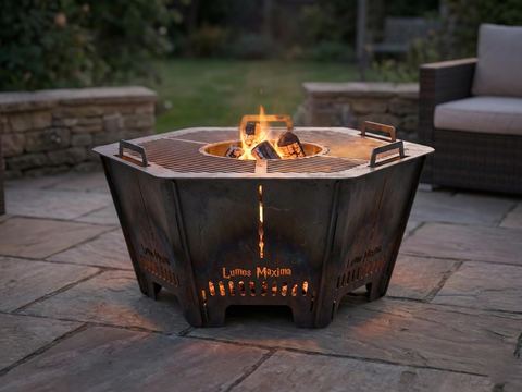Hexagon steel fire pit burning on a stone patio
