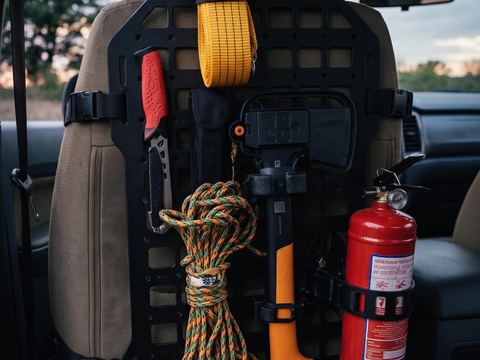 MOLLE panel on a car seat back holding rope, an axe and a fire extinguisher